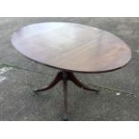 A reproduction oval mahogany breakfast table, the reeded top with two drop-leaves inlaid with