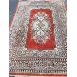 An oriental style wool carpet woven with floral medallion in russet field framed by multiple