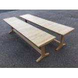 A pair of contemporary oak benches, the rectangular plank seats on tapering tresle style supports