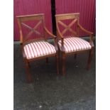 A pair of hardwood elbow chairs, the backs with moulded crossed battens centering on carved oval