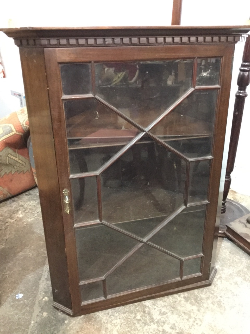 A stained mahogany corner cabinet with moulded dentil cornice above astragal glazed door enclosing