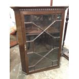 A stained mahogany corner cabinet with moulded dentil cornice above astragal glazed door enclosing