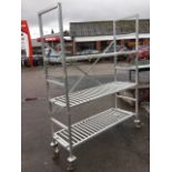 A rectangular aluminium shelving unit with grill shelves on tubular supports, raised on casters. (