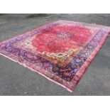 An oriental carpet woven with central flowerhead medallion with busy pink field of flowers, framed