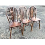 A set of three elm wheelback kitchen chairs, the hooped spindlebacks above solid seats, raised on