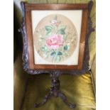 A small Victorian rosewood screen, the frame containing an oval two sided rose embroidered panel, in