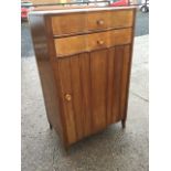 A mid-century cushion fronted walnut cabinet, the rectangular top above two drawers and shaped door,