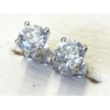 A pair of diamond stud earrings, the brilliant cut circular claw set stones of nearly one-and-a-half