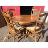 A circular European oak extending dining table with spare leaf, and a set of four stickback chairs