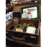 A leather suitcase containing miscellaneous collectors items including binoculars, tins, naval