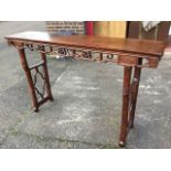 A Chinese alter table with rectangular panelled top in moulded frame above pierced aprons carved