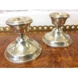 A pair of hallmarked silver dwarf candlesticks of urn form on circular moulded bases with ribbed