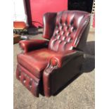 An ox-blood leather reclining armchair, with studded button upholstery, the seat with loose cushion,