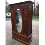 An Edwardian inlaid mahogany wardrobe with moulded ogee cornice above an oval bevelled mirror door