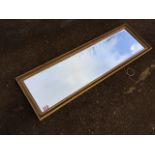 A rectangular gilt framed mirror, the bevelled plate in fluted frame. (46.5in x 14.5in)