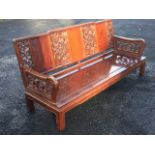 A Chinese hardwood sofa, the back carved with pierced scrolled panels above a deep solid seat, the