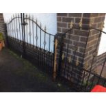 A pair of arched wrought iron driveway gates with fleur-de-lils spear finials to vertical bars,