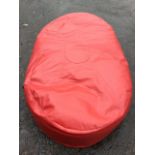 A large oval red leather beanbag, stitched with segmented panels. (67in)
