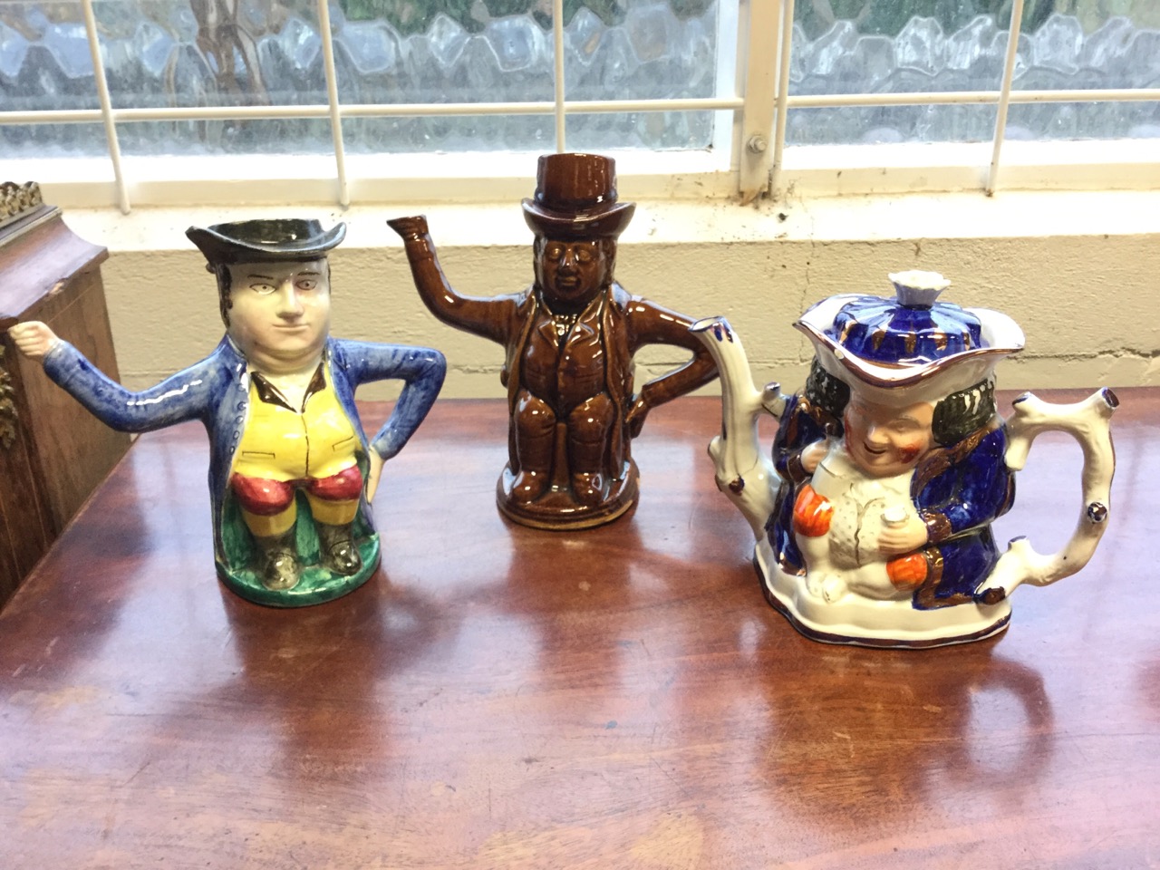 A nineteenth century stoneware treacle glazed teapot toby with lid; a gaudy welsh style teapot &