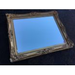 A large mirror, the rectangular plate in an old gilt & gesso frame with foliate scrolled mounts. (