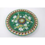 19th Century Majolica glazed charger with tube lined lilies and geometric border,