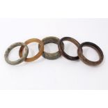 Five Chinese carved jade or hardstone bangles the largest 9cm diameter.