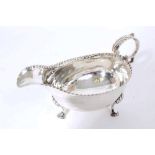 George IV silver sauce boat of small proportions, with punched rim and open scroll handle,