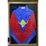A display frame containing jockey silks, royal blue body with triple yellow diamond and red sleeves,
