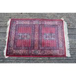 Small part silk Pakistani Tekke rug of typical form with claret red ground and twin square reserves