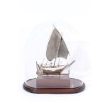 20th century Chinese white metal model of a boat with single sail sitting in a white metal cradle