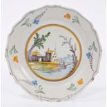 18th century French faience plate painted with buildings and floral sprays, 23cm,