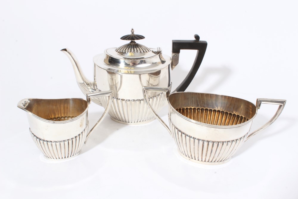 George V silver teapot of half fluted form with angular ebony handle and hinged domed and fluted