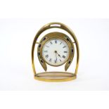 Victorian brass desk clock with circular movement and white enamel dial surrounded by a horseshoe