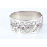 Irish silver hinged bangle with engraved decoration and three synthetic rubies.
