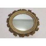 Large oval gilt gesso wall mirror in moulded frame with relief pierced floral garland border,