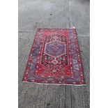 Iranian rug with central geometric medallion within aubergine ground with scattered animal and