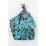 Large turquoise stone pendant with silver mounts.