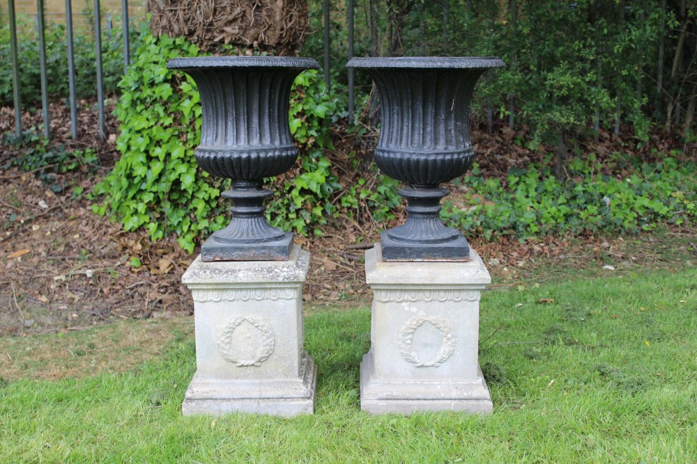 Pair of cast iron urns, campana form with removable rim, black painted, 55cm high, raised on