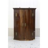 George III mahogany bow front hanging corner cupboard with painted interior enclosed by two doors