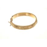 Gold (9ct) bangle with engraved floral scroll decoration, 18cm