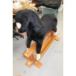 Rocking horse with plush covering on wooden cantilever base.