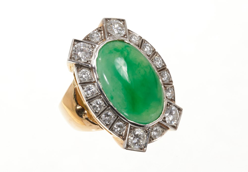 Jade and diamond cluster ring with an oval green jade cabochon surrounded by brilliant cut diamonds