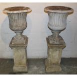 Pair of Classical style garden urns, each of fluted form, 60c, high raised on square plinth and