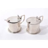 Two similar Edwardian silver mustard pots with engraved crests