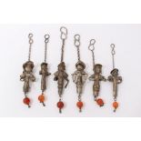Six old Chinese white metal pendants, each modelled as a figure, suspending a carnelian bead