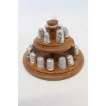 Collection of silver and white metal thimbles on two tier wooden stand
