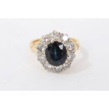 Sapphire and diamond cluster ring with an oval mixed cut blue sapphire measuring approximately