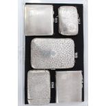 Two late Victorian silver cigarette cases with scroll engraved decoration and three other silver