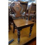 A Victorian mahogany shield back hall chair with scroll decoration and solid seat, set on turned