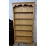 A 3' 2" modern waxed pine six shelf shallow open bookcase, set on shaped apron